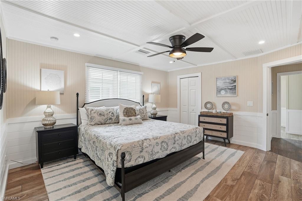 Bedroom featuring wainscoting, wood finished floors, a closet, a ceiling fan, and recessed lighting - Virtually Edited Image