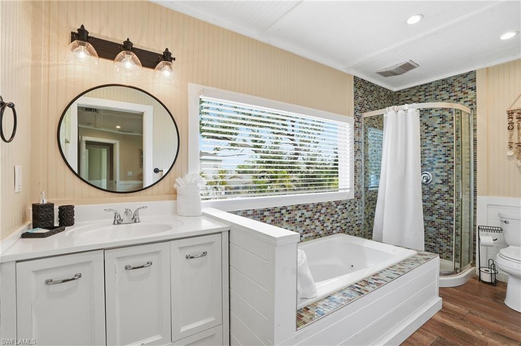 Full bathroom with a shower stall, vanity, a whirlpool tub, dark wood-style floors, and recessed lighting - Virtually Edited Image