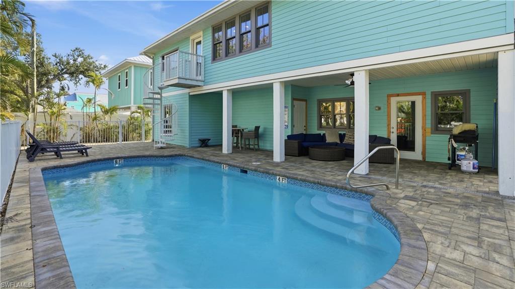 View of pool with outdoor lounge area, a patio, a grill, and a balcony