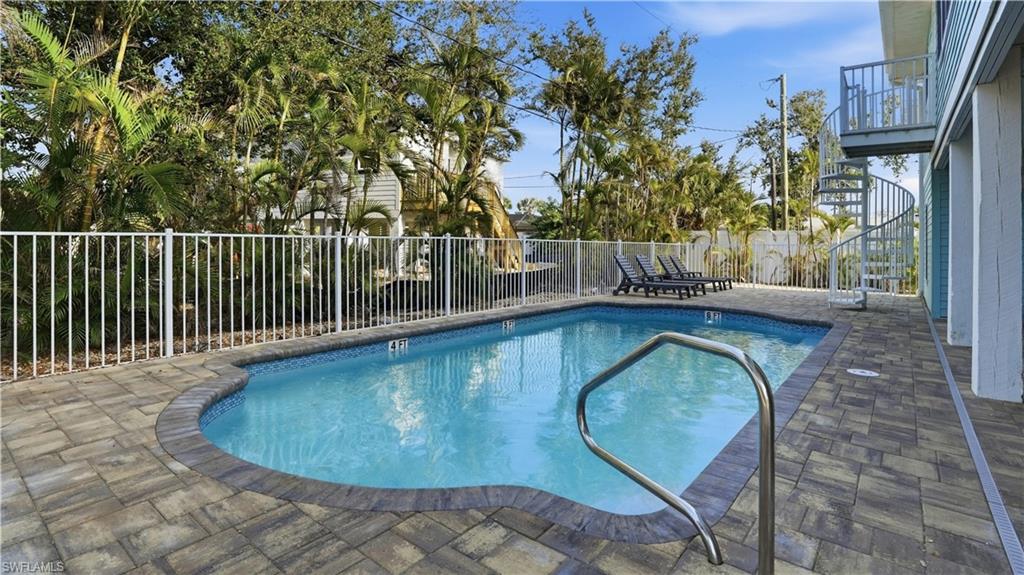 Community pool with a patio area, a fenced backyard, and stairway