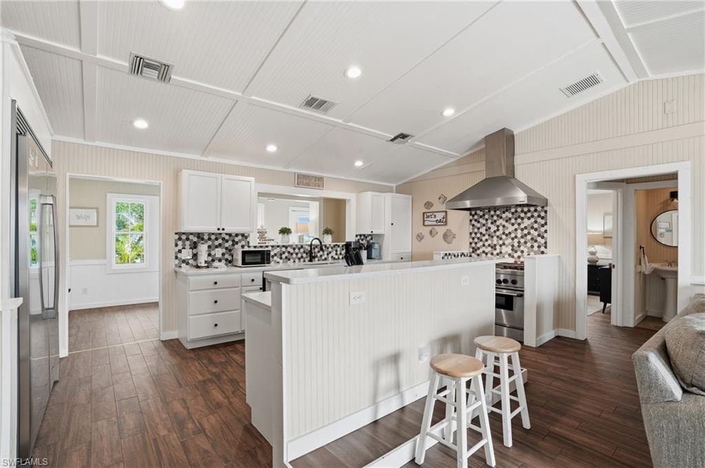 Kitchen with white cabinets, decorative backsplash, light countertops, wall chimney exhaust hood, and dark wood-type flooring - Virtually Edited Image