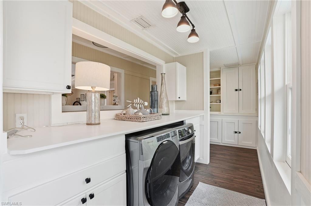 Laundry room with dark wood-style floors, washer and dryer, and cabinet space - Virtually Edited Image