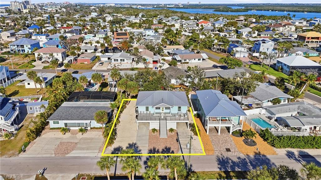 Aerial view of residential area with property boundaries highlighted and a nearby body of water - Virtually Edited Image
