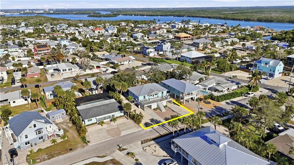 Aerial view of residential area with a nearby body of water and property parcel outlined
