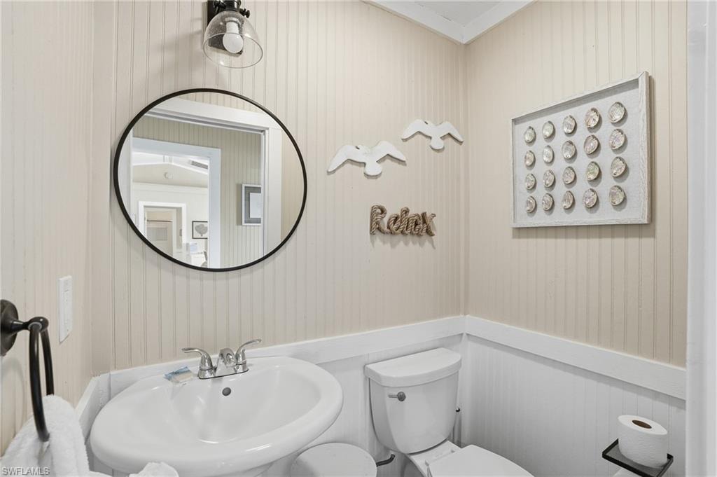 Half bath featuring crown molding and toilet - Virtually Edited Image