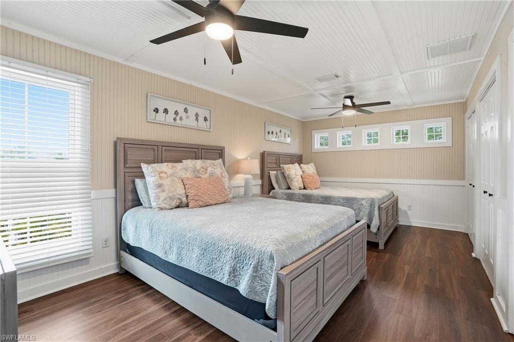 Bedroom with dark wood-style flooring, a closet, ceiling fan, a wainscoted wall, and ornamental molding - Virtually Edited Image