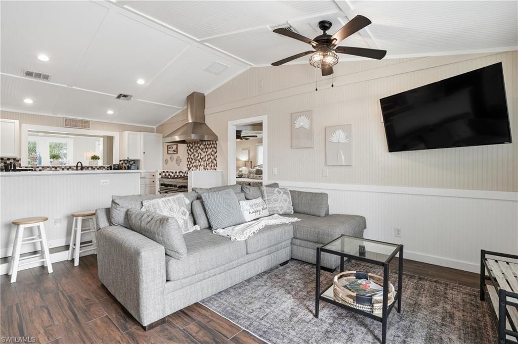 Living room with lofted ceiling, dark wood finished floors, a wainscoted wall, and wooden walls - Virtually Edited Image