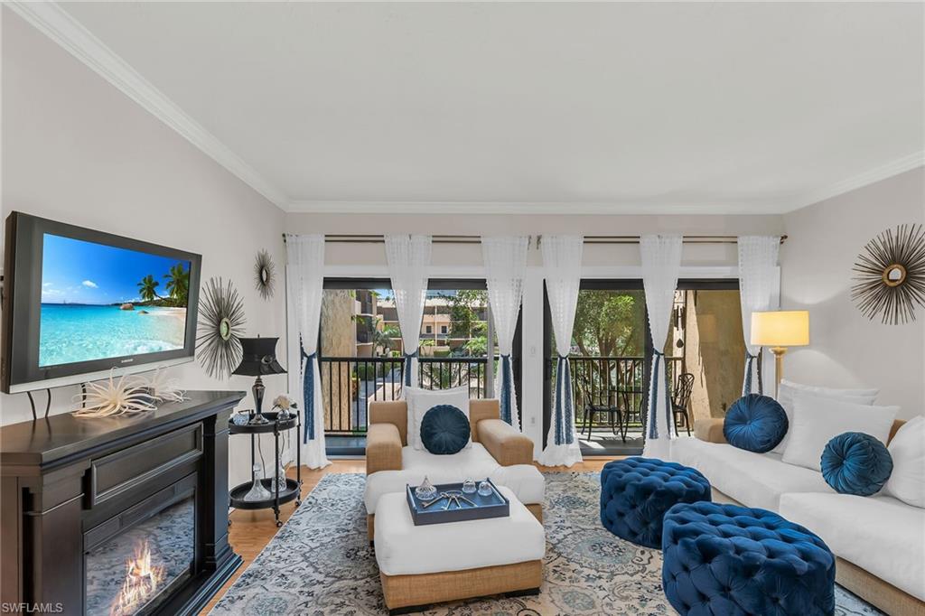 Living room with crown molding, a lit fireplace, and wood finished floors