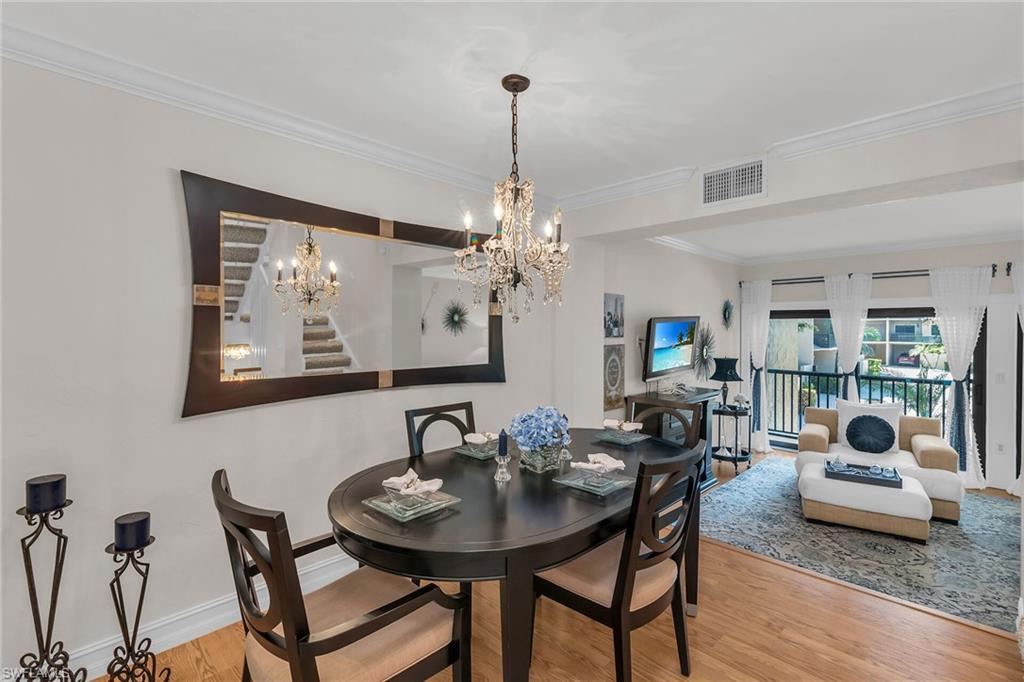 Dining room with light wood finished floors, ornamental molding, a chandelier, and stairway