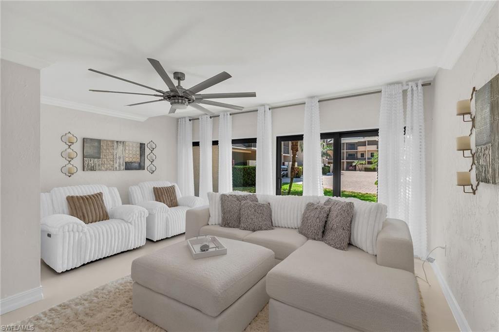 Living room with a textured wall, ornamental molding, and a ceiling fan