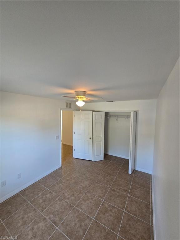 Unfurnished bedroom with a closet, a ceiling fan, and dark tile patterned floors