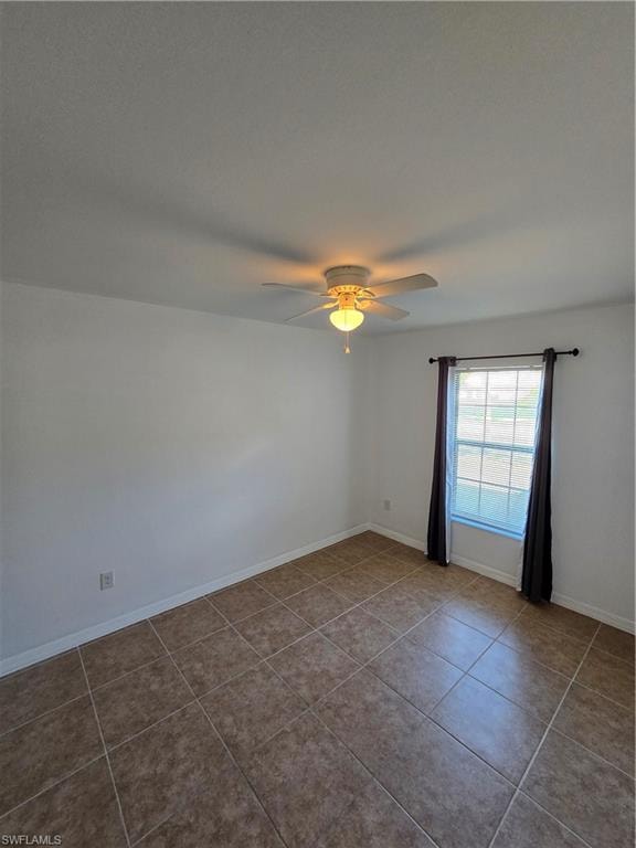 Empty room featuring a ceiling fan and tile patterned flooring