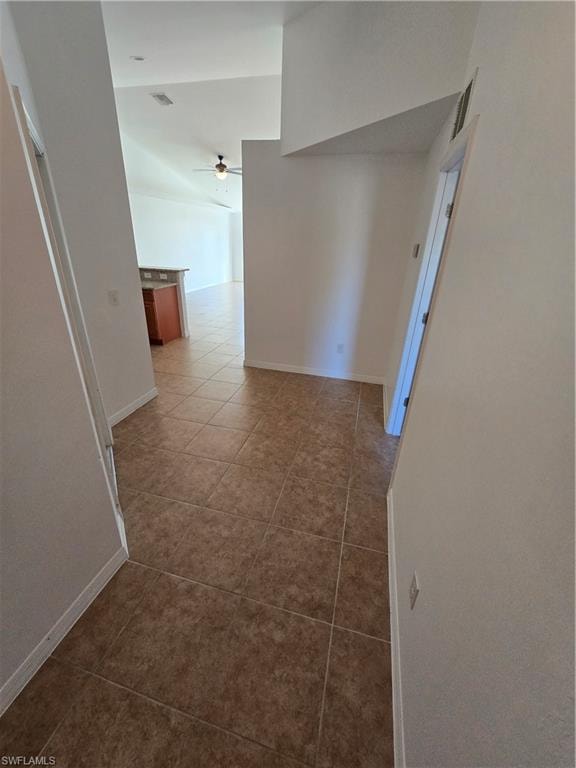 Hall with light tile patterned flooring and vaulted ceiling