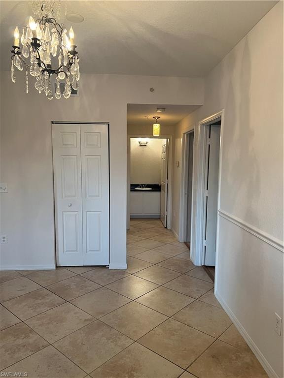 Corridor with a chandelier and light tile patterned flooring