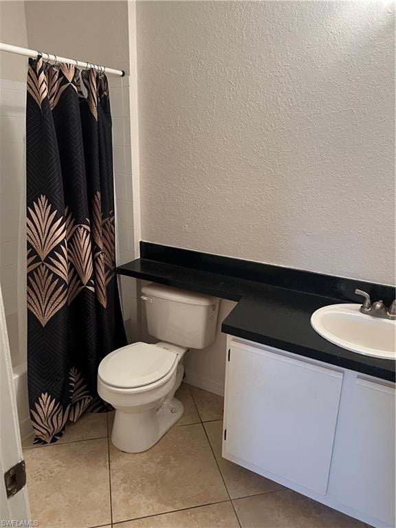 Bathroom featuring a textured wall, vanity, shower / tub combo with curtain, and light tile patterned floors