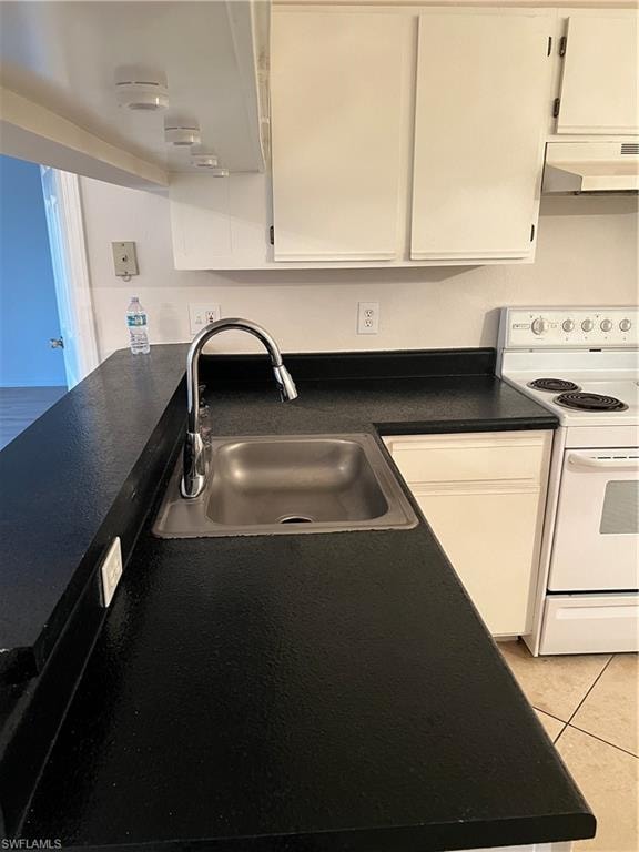 Kitchen with black stove, dark countertops, extractor fan, light tile patterned floors, and white cabinetry