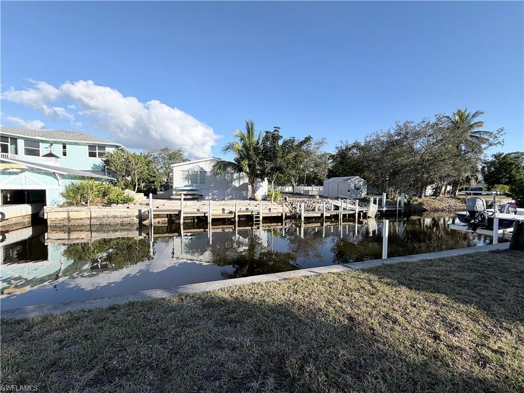 Dock area featuring a water view, a lawn, and a residential view