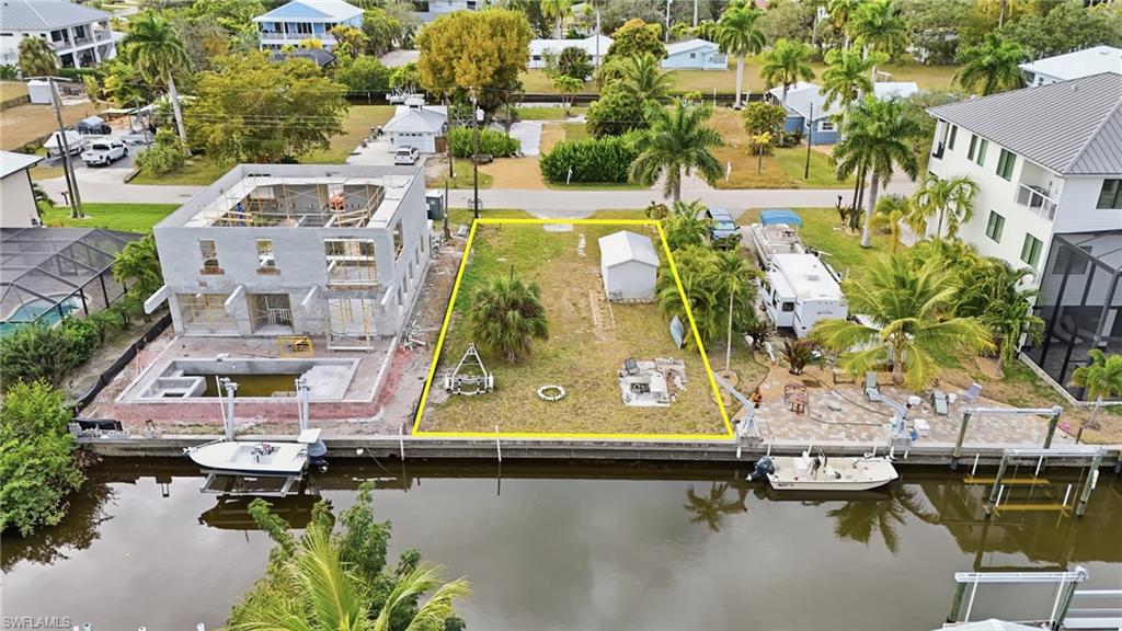 Aerial perspective of suburban area with property boundaries highlighted and a large body of water
