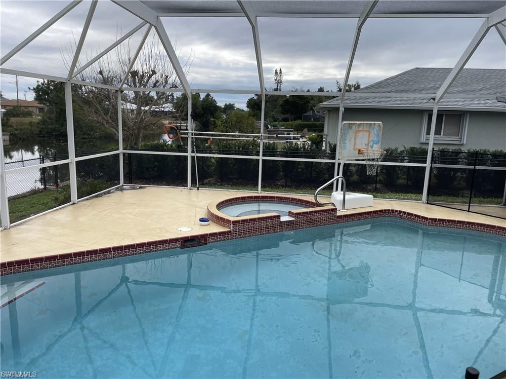 View of pool featuring a sunroom, glass enclosure, and a pool with connected hot tub