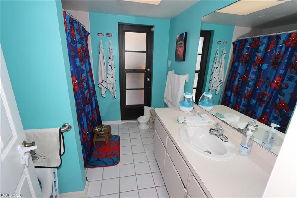 Full bath featuring vanity, light tile patterned floors, and curtained shower