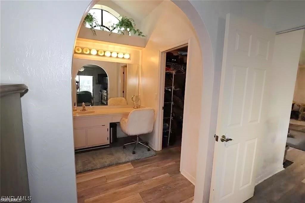 Bathroom with vanity, wood finished floors, and a walk in closet