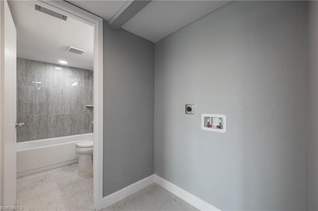 Washroom with hookup for a washing machine, light marble finish flooring, and electric dryer hookup