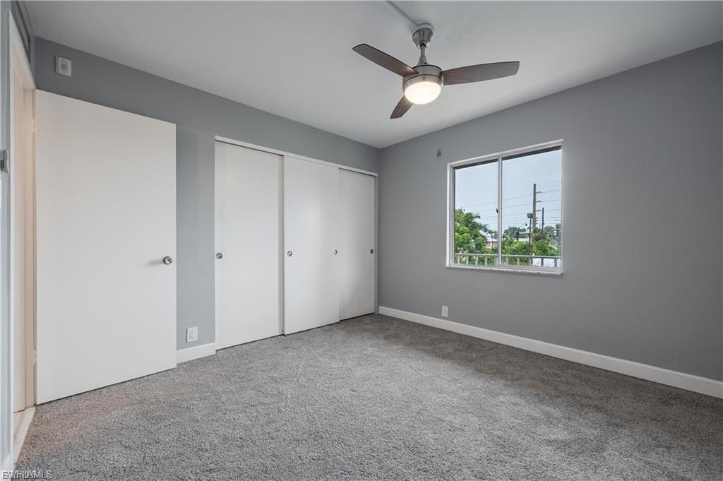 Unfurnished bedroom featuring a closet, light carpet, and a ceiling fan