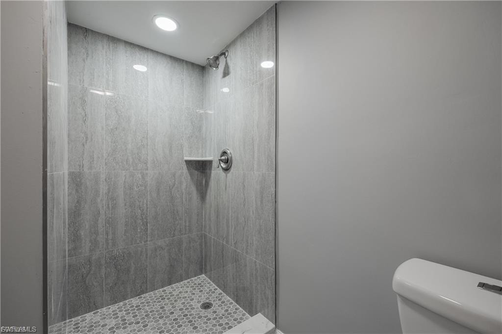 Full bathroom with tiled shower and recessed lighting