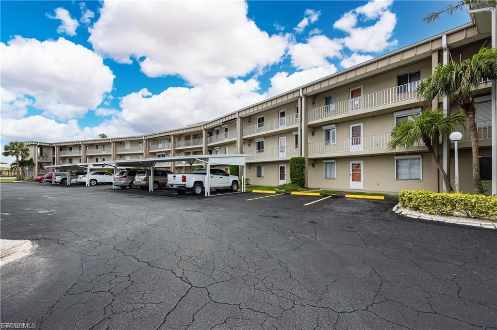 View of apartment building / complex with covered and uncovered parking