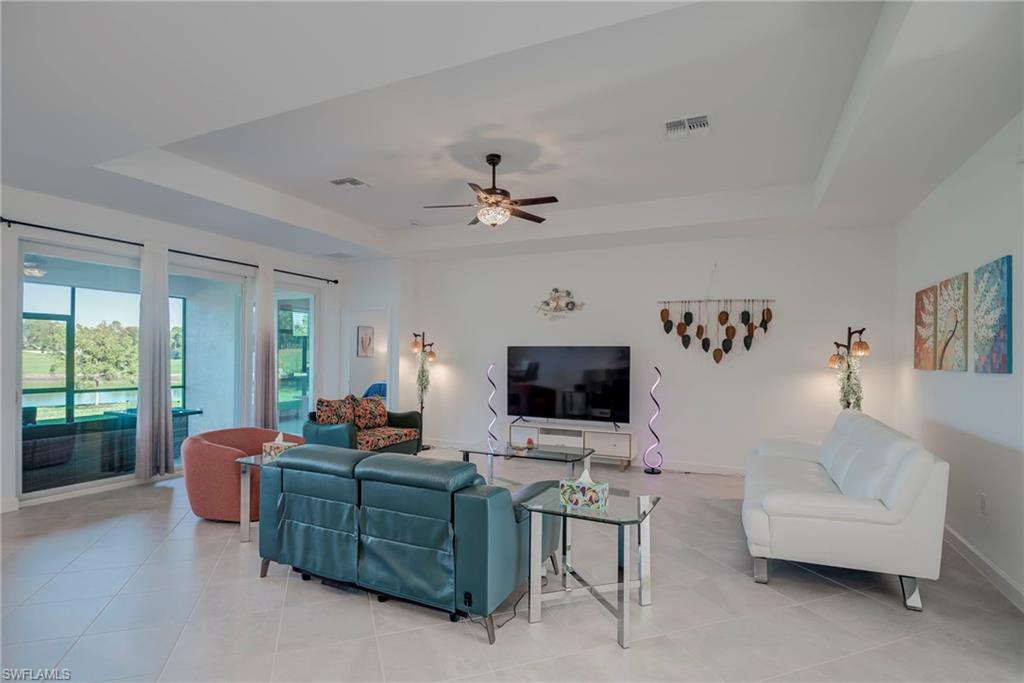 Living area with a raised ceiling, ceiling fan, and light tile patterned floors