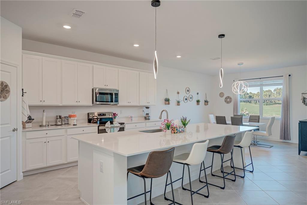 Kitchen with appliances with stainless steel finishes, a kitchen breakfast bar, decorative light fixtures, a kitchen island with sink, and recessed lighting