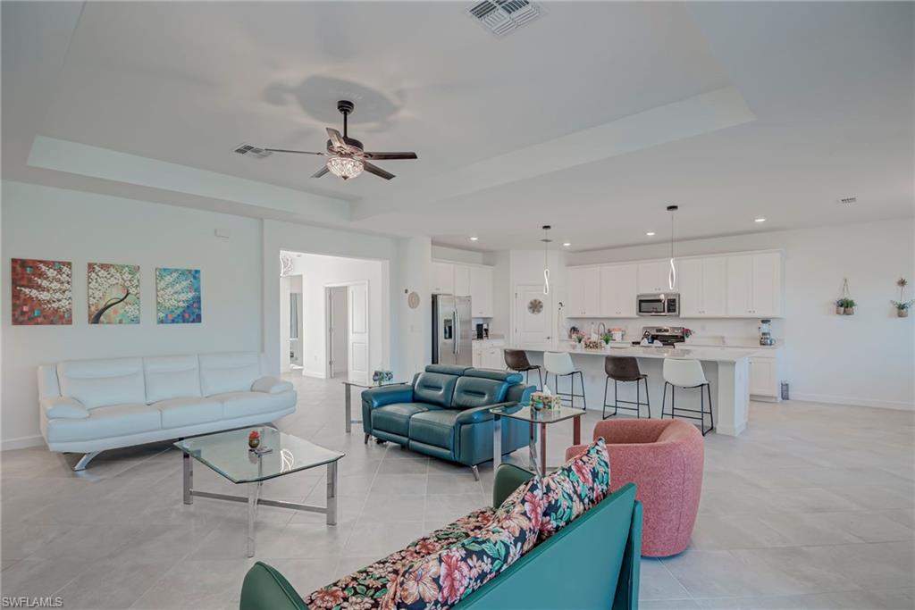 Living area featuring a raised ceiling, recessed lighting, and a ceiling fan