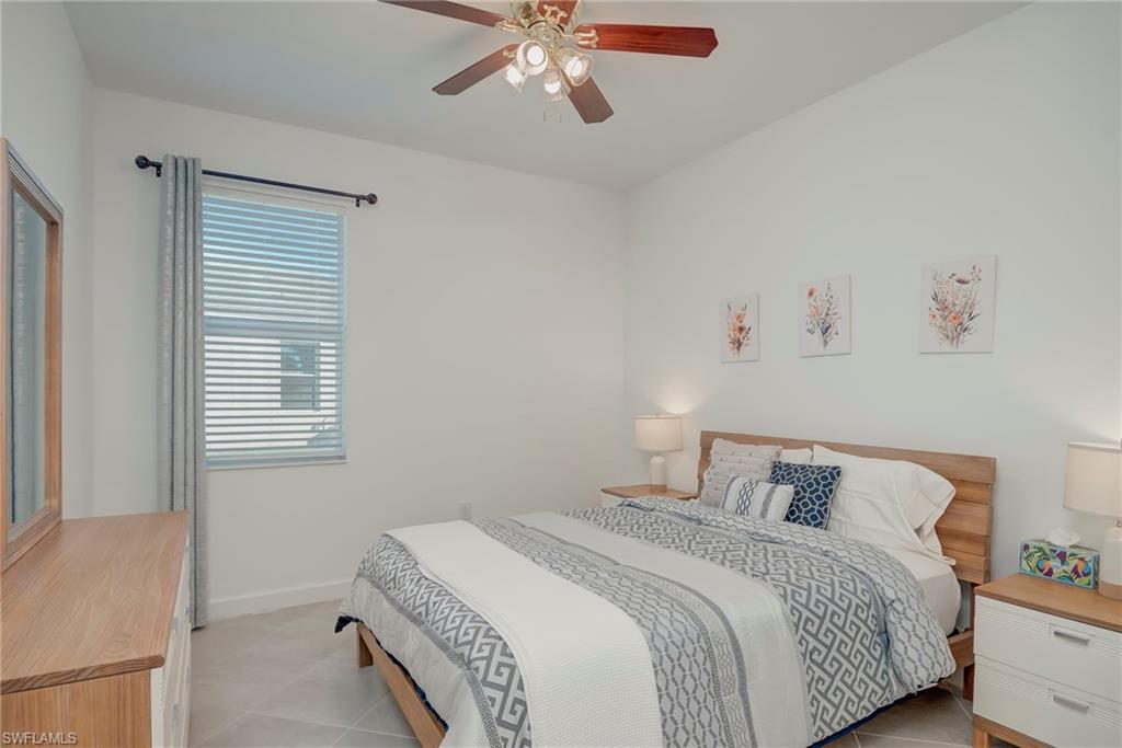 Tiled bedroom featuring a ceiling fan and baseboards