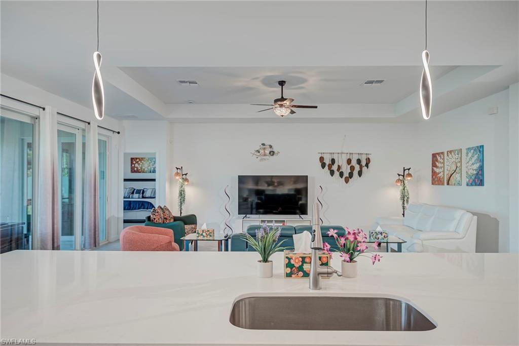 Kitchen featuring decorative light fixtures, a tray ceiling, and light stone counters