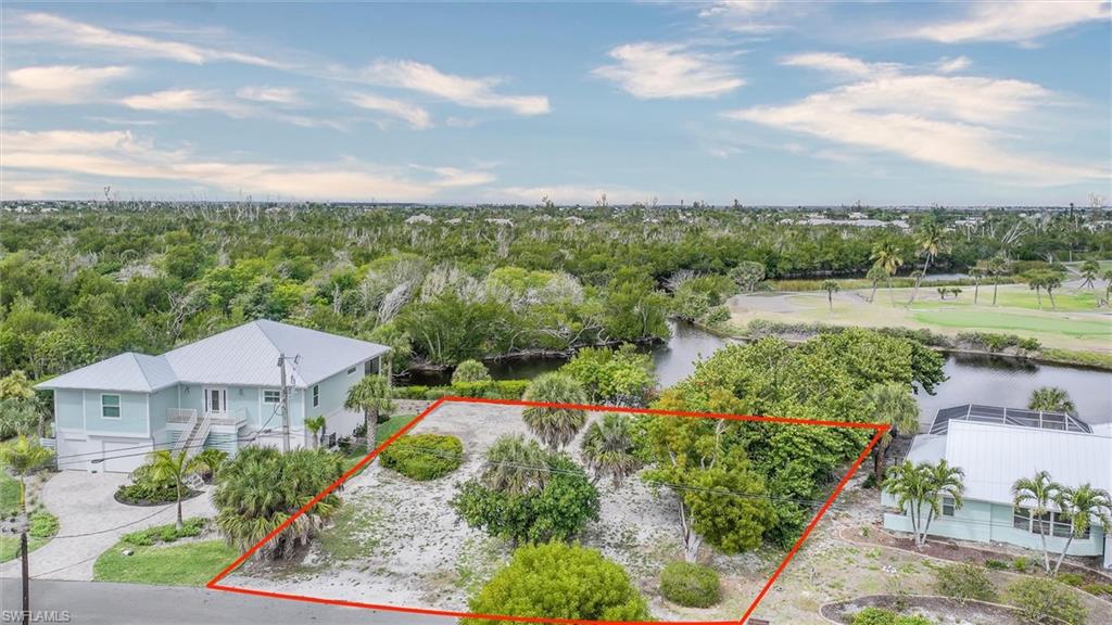 Aerial view of property and surrounding area featuring property parcel outlined and a nearby body of water