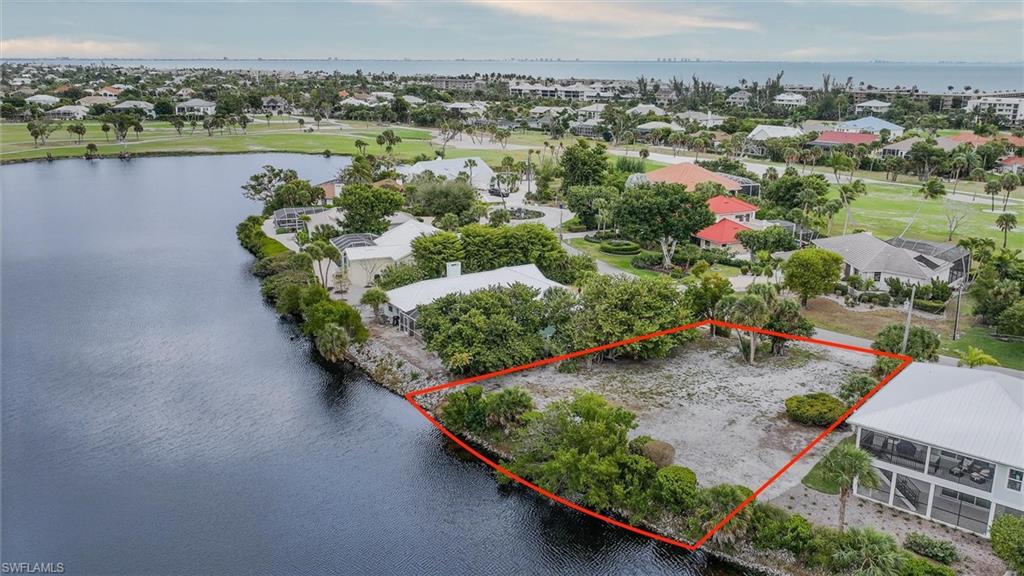 Aerial view of residential area with a nearby body of water and property parcel outlined
