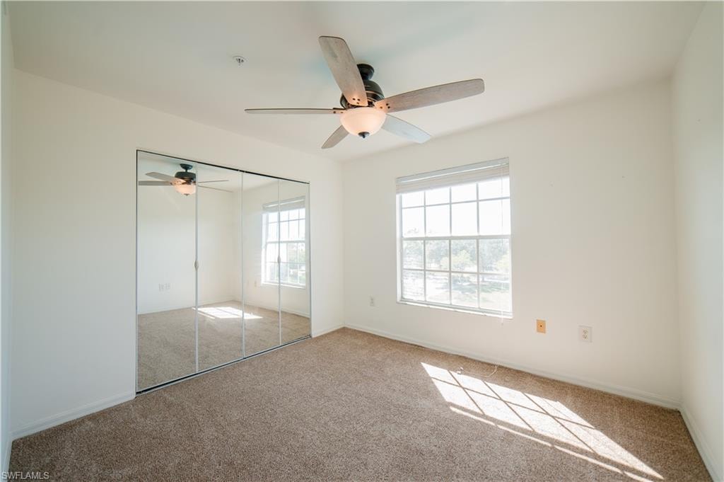 Unfurnished bedroom with carpet, a closet, and a ceiling fan