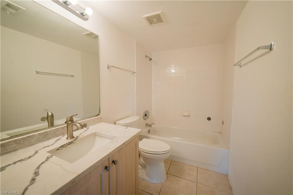 Full bath featuring vanity, bathtub / shower combination, and light tile patterned flooring