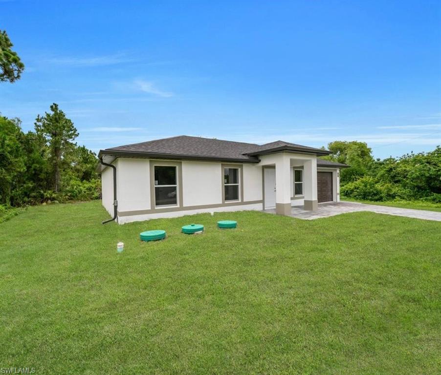 Prairie-style home with a front lawn, concrete driveway, an attached garage, and stucco siding