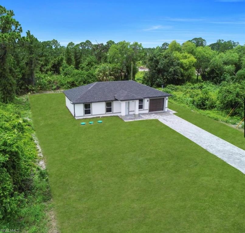 Ranch-style home with a front lawn, driveway, roof with shingles, and an attached garage