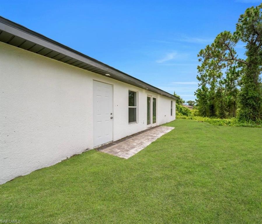View of green lawn featuring a patio and french doors