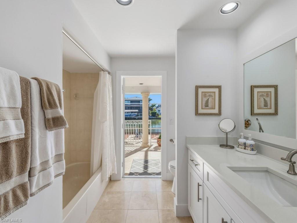 Bathroom featuring shower / tub combo with curtain, light tile patterned floors, vanity, and recessed lighting