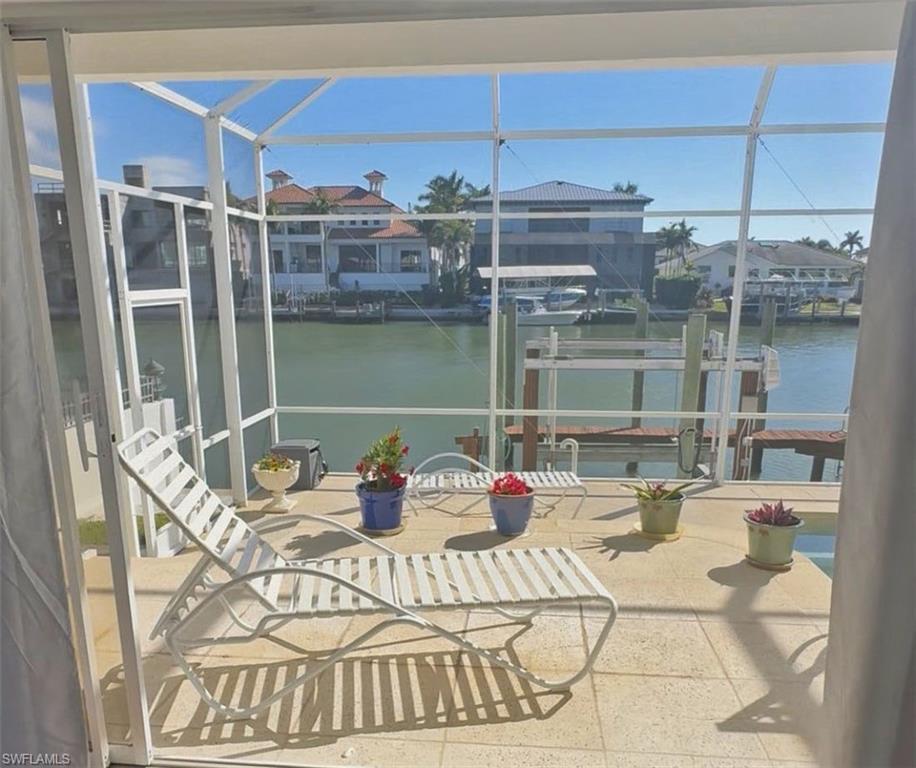 Dock area featuring boat lift, a sunroom, a patio area, and a water view