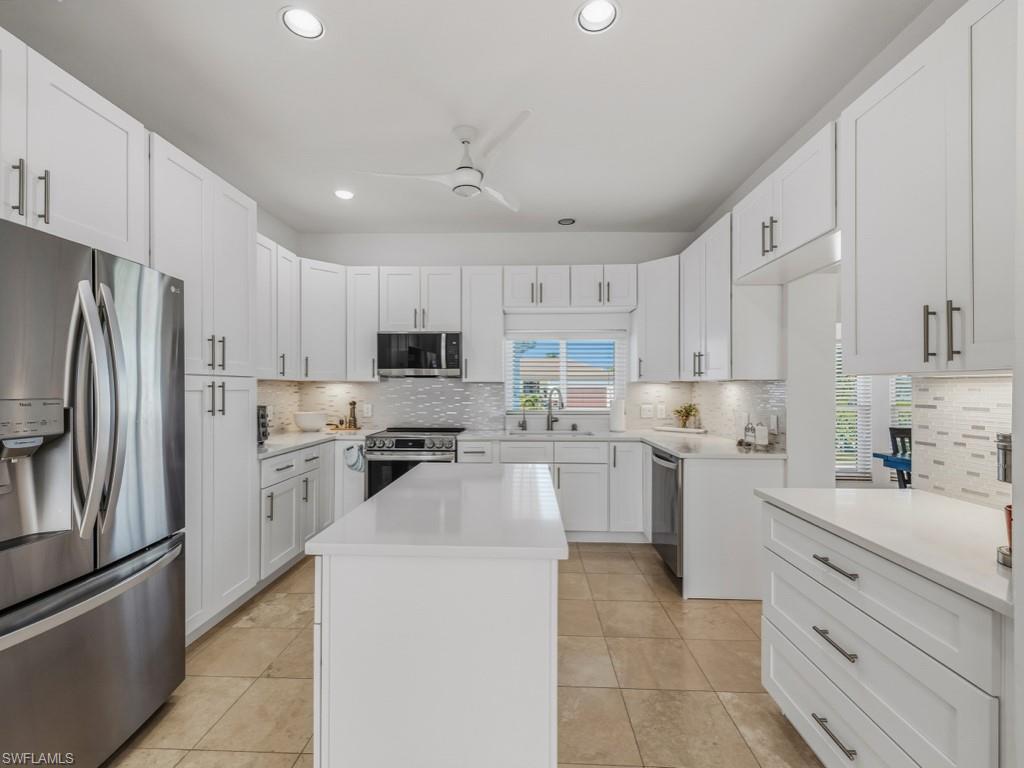 Kitchen with stainless steel appliances, white cabinets, a kitchen island, recessed lighting, and tasteful backsplash