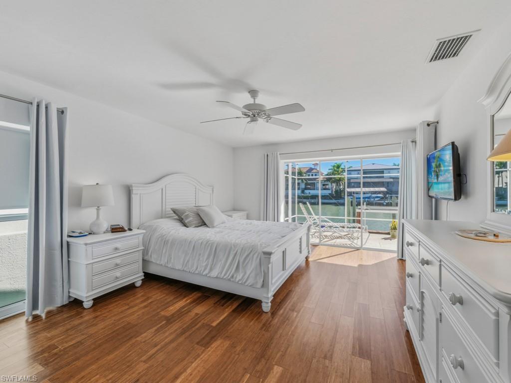 Bedroom with access to exterior, dark wood finished floors, and a ceiling fan
