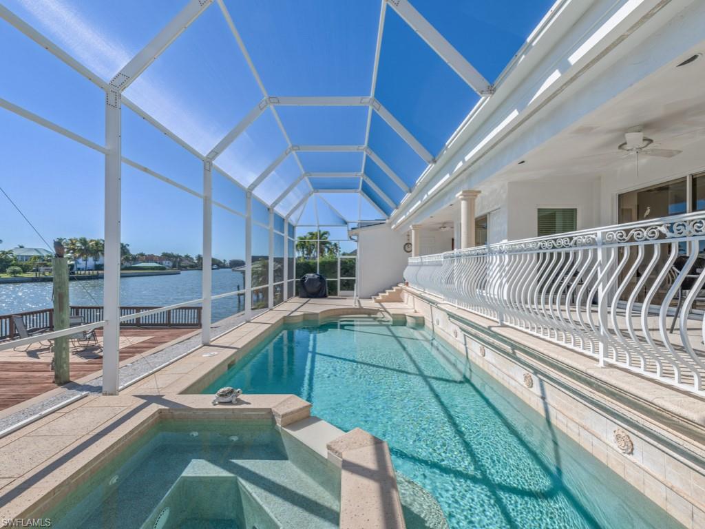 View of pool with a sunroom, a lanai, a patio area, a water view, and a pool with connected hot tub