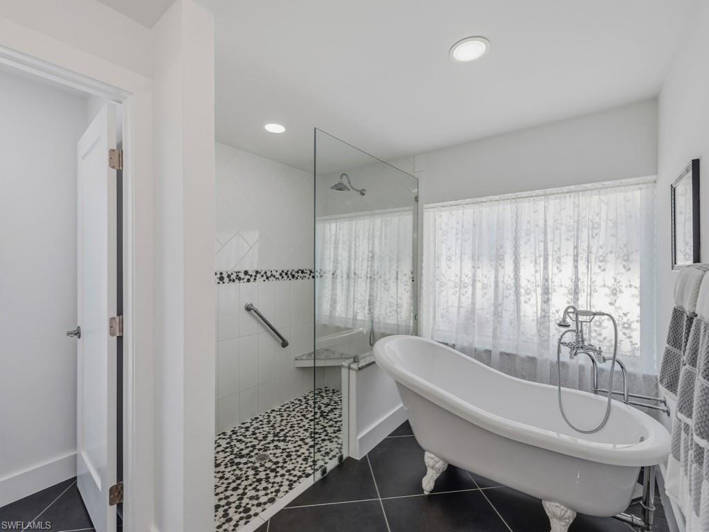 Full bathroom featuring a walk in shower, a freestanding tub, dark tile patterned floors, healthy amount of natural light, and recessed lighting