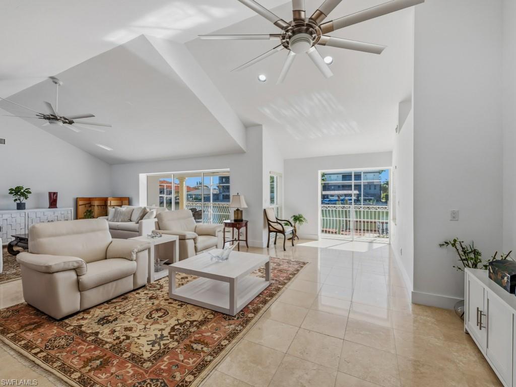 Living room with ceiling fan, vaulted ceiling, and light tile patterned floors