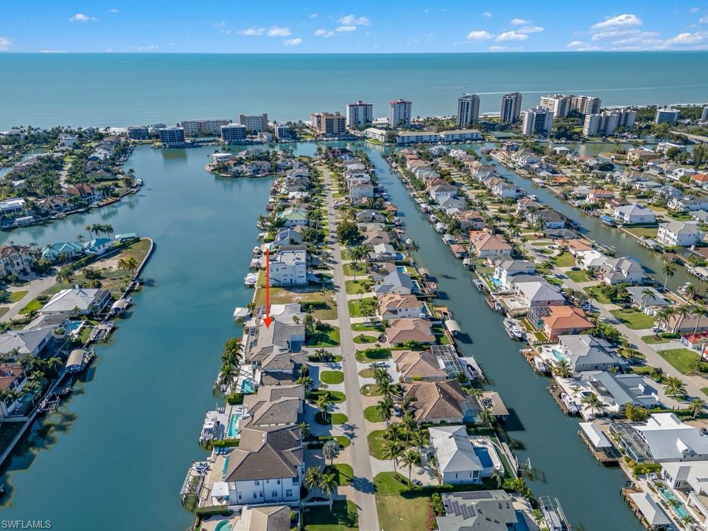 Aerial view of property and surrounding area featuring a nearby body of water and nearby suburban area