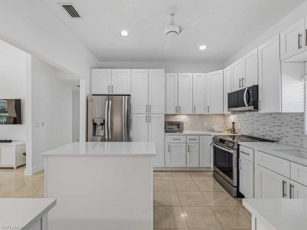 Kitchen with white cabinets, a center island, appliances with stainless steel finishes, decorative backsplash, and recessed lighting
